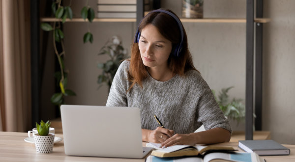 Focused woman studying online with headphones and laptop at a desk